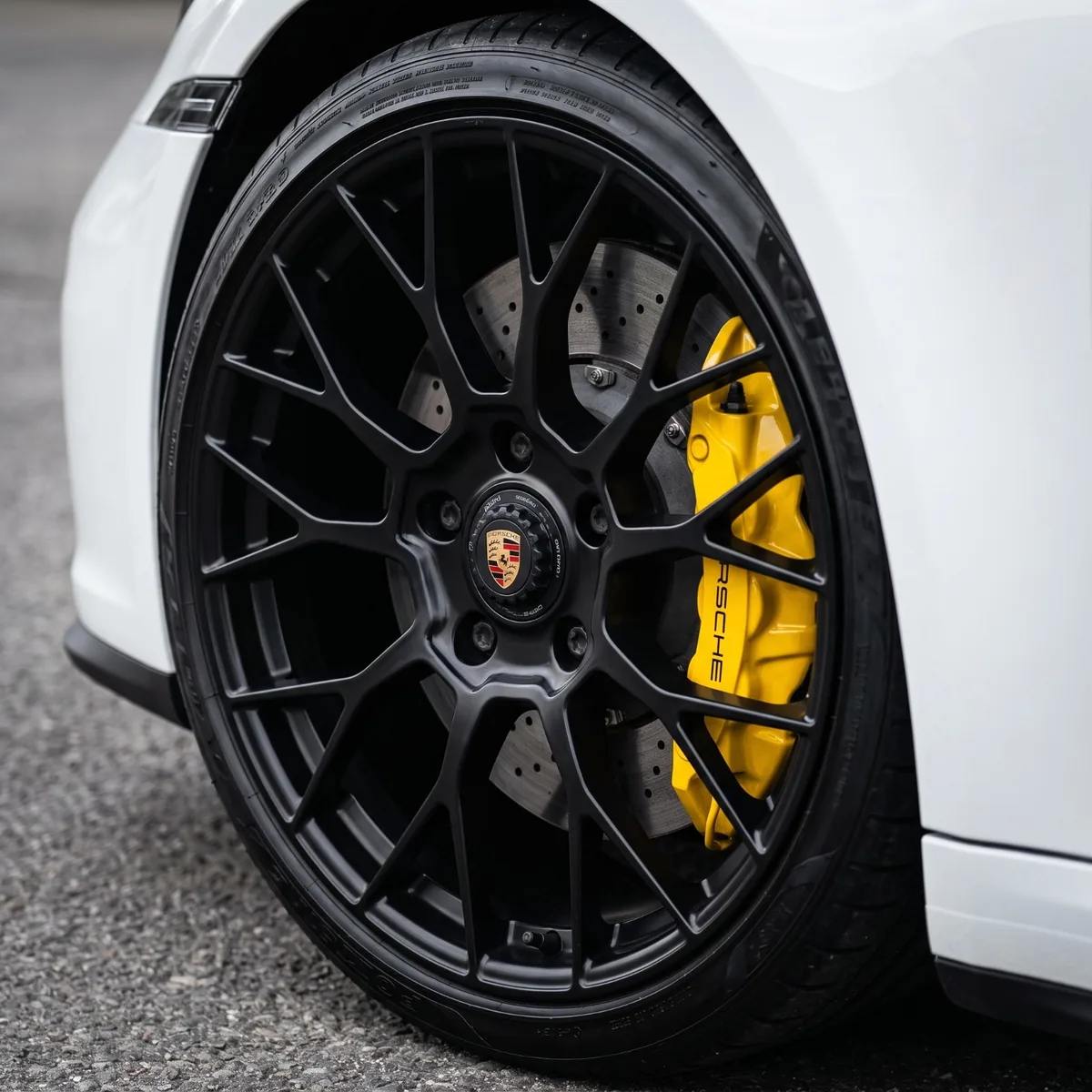 Matte black Porsche wheel with a yellow brake caliper